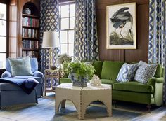 a living room with green couches and blue chairs in front of a painting on the wall