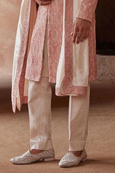 Coral matka silk sherwani, accentuated with all over resham embroidery and adorned with tonal beadwork. Paired with a blush monga tussar kurta and cotton lycra trouser.
Components: 3
Pattern: Embroidery
Type Of Work: Resham, Beads
Neckline: Stand Collar
Sleeve Type: Full Sleeves
Fabric: Sherwani: Matka Silk, Kurta: Monga Tussar, Trouser: Cotton Lycra
Color: Peach
Other Details: 
Model height: 6ft, wearing size M
Note: The belt, shawl, footwear and safa worn  by the model is not for sale
Occasion Unstitched Pearl Embroidered Sherwani With Traditional Drape, Traditional Semi-stitched Sherwani With Cutdana Details, Semi-stitched Chinon Sherwani With Intricate Embroidery, Pink Semi-stitched Sherwani With Intricate Embroidery, Luxury Semi-stitched Ceremonial Sherwani, Beaded Neckline, Silk Embroidery, Full Sleeve, Stand Collar