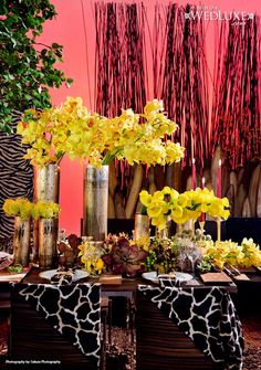 there are many vases and flowers on the table with zebra print cloth around them