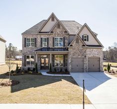 a large brick house with two garages and lots of grass in front of it