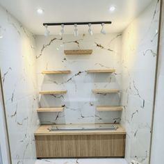 an empty bathroom with marble walls and shelves