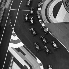 black and white photograph of an aerial view of cars driving on a race track,