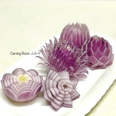 three purple flowers sitting on top of a white plate