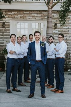 a group of men standing next to each other in front of a brick building with palm trees