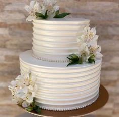 a three tiered cake with white flowers on top