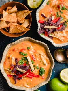 two bowls filled with salsa, tortilla chips and lime wedges on a table