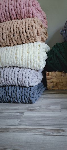 a pile of folded towels sitting on top of a wooden floor next to a basket