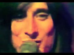 a man with long hair is singing into a microphone