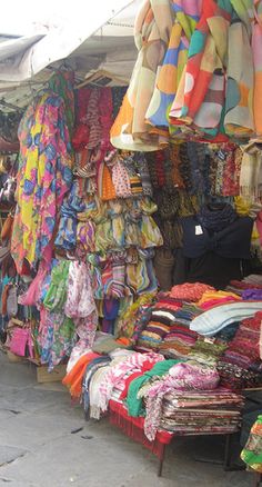 an open air market with umbrellas and clothes for sale