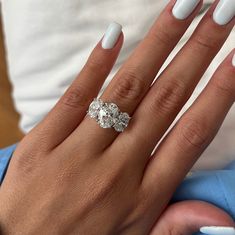 a woman's hand with white manicured nails and an oval shaped diamond ring