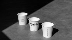 three white cups sitting on top of a cement floor