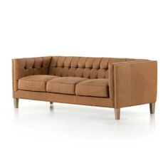 a tan leather couch with wooden legs