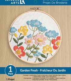 an embroidery kit with flowers and leaves on the front is shown in white, blue, yellow and pink colors