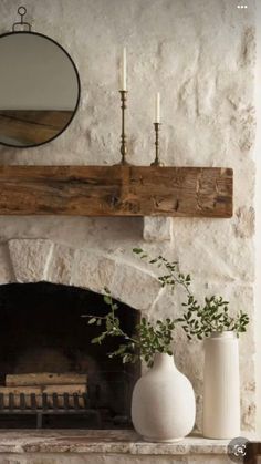 a fireplace with a mirror above it and vases on the mantle next to it