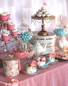 a table topped with lots of candy and cupcakes next to a cake stand