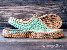 a pair of crocheted shoes sitting on top of a wooden floor next to a piece of wood