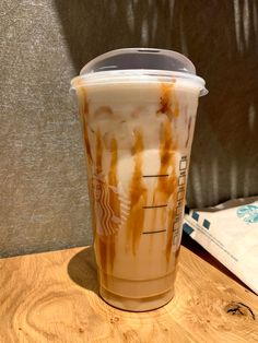 a starbucks drink with caramel on the side sitting on top of a wooden table