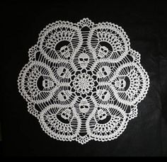 a white doily sitting on top of a black cloth covered in crochet