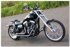 a black and silver motorcycle parked on the side of a road next to some grass