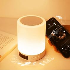 an alarm clock sitting on top of a table next to a book and cell phone