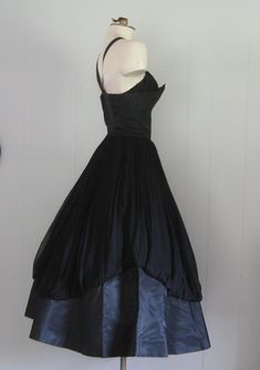 APPROXIMATE MEASUREMENTS (INCHES): Current Size: XS/S Tag size: 10 (please note this is vintage sizing; see measurements for more accurate current size/fit) Bust: 34 Waist: 25 Hip: OPEN Bodice (shoulder to waist): 17 Skirt (waist to hem): 32 CONDITION Excellent DESCRIPTION 1950s party dress Black taffeta and black chiffon fabric Fitted bodice and full skirt Back metal zip closure No manufacturer's label Vintage Fitted Evening Gown, Fitted Evening Dress With Full Skirt, Fitted Gown With Full Skirt For Party, Vintage Sleeveless Evening Dress For Prom Season, Vintage Sleeveless Evening Dress For Prom, Vintage Sleeveless Prom Evening Dress, Vintage Ball Gown With Fitted Bodice, Evening Dresses With Boned Bodice, Tea Length, Elegant Vintage Ball Gown For Party