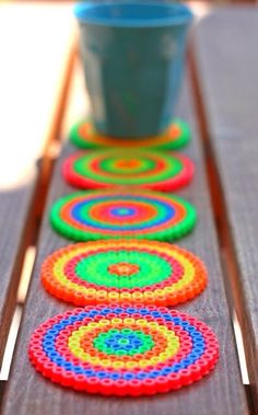 a row of multicolored circles sitting on top of a wooden table next to a potted plant