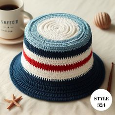 a crocheted hat sitting on top of a bed next to a cup of coffee