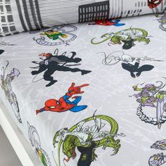 a bed with spiderman and other cartoon characters printed on it's coverlet