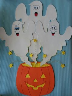 three ghost cutouts sitting on top of a pumpkin