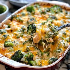 a casserole dish with broccoli and cheese being lifted by a spoon