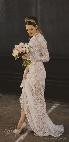 a woman in a long white dress holding a bouquet of flowers and wearing high heels