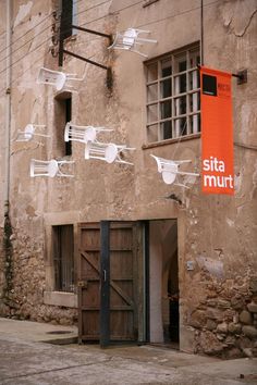 an orange sign hanging from the side of a building next to a door and window