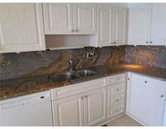 a kitchen with marble counter tops and white cabinets