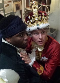 two people dressed in costumes posing for a photo with a crown on top of their head