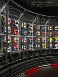 there are many different cars on display in this room, and the wall is covered with metal mesh