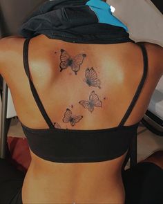 the back of a woman's body with butterflies tattooed on her upper and lower back