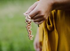 a person holding a wooden keychain with a snake on it