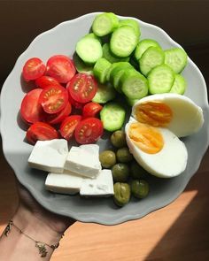 a plate with cucumbers, tomatoes, olives, and cheese on it