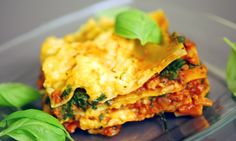 a plate topped with lasagna covered in cheese and spinach leafy greens