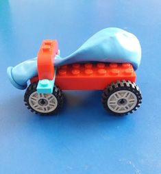 a toy car made out of legos sitting on a blue surface with wheels and tires