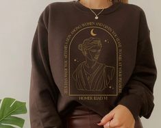 a woman wearing a brown sweatshirt with an image of the statue of liberty on it