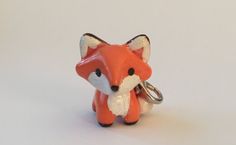 a red fox keychain is shown on a white surface, with the tail curled up