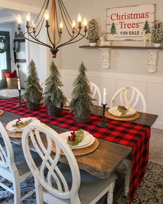 a dining room table decorated for christmas with pine trees on the top and plaid runner