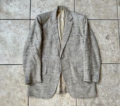 "Here is a vintage sport coat by \"G. Verma,\" that can be dated to the 1960s. It was a custom-made piece, so there is no tag, but it measures most like a 36 or 37 Regular; still, please use the measurements provided to ensure a proper fit. Made of what is assuredly a wool/silk blend, it has a light gray background and textured black & brown flecks throughout. Additionally, it is fully canvassed and fully lined, and it further features great details, like: a 2-button darted front, slanted hip po Vintage Tailored Sport Coat With Welt Pockets, Vintage Blazer With Flat Front For Tailoring, Vintage Fitted Sport Coat, Vintage Semi-formal Sport Coat, Tweed Sport Coat, Mens Sport Coat, Herringbone Tweed, Orange Plaid, Tweed Blazer