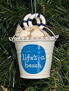 a life's a beach bucket ornament hanging from a christmas tree