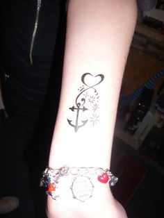 a woman's arm with an anchor and heart tattoo on it