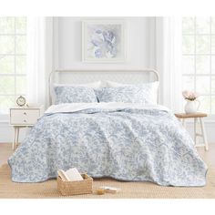 a bed with blue and white bedspread in a bedroom next to a window