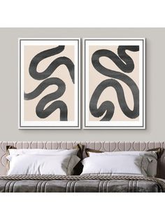 two black and white paintings on the wall above a bed