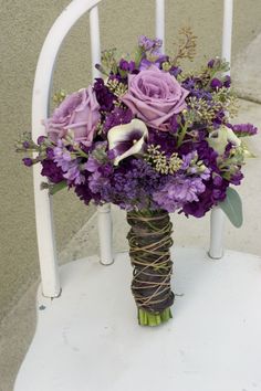 a bouquet of purple flowers sitting on top of a white chair