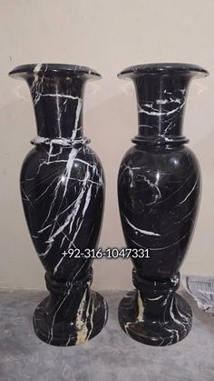 two black marble vases sitting next to each other